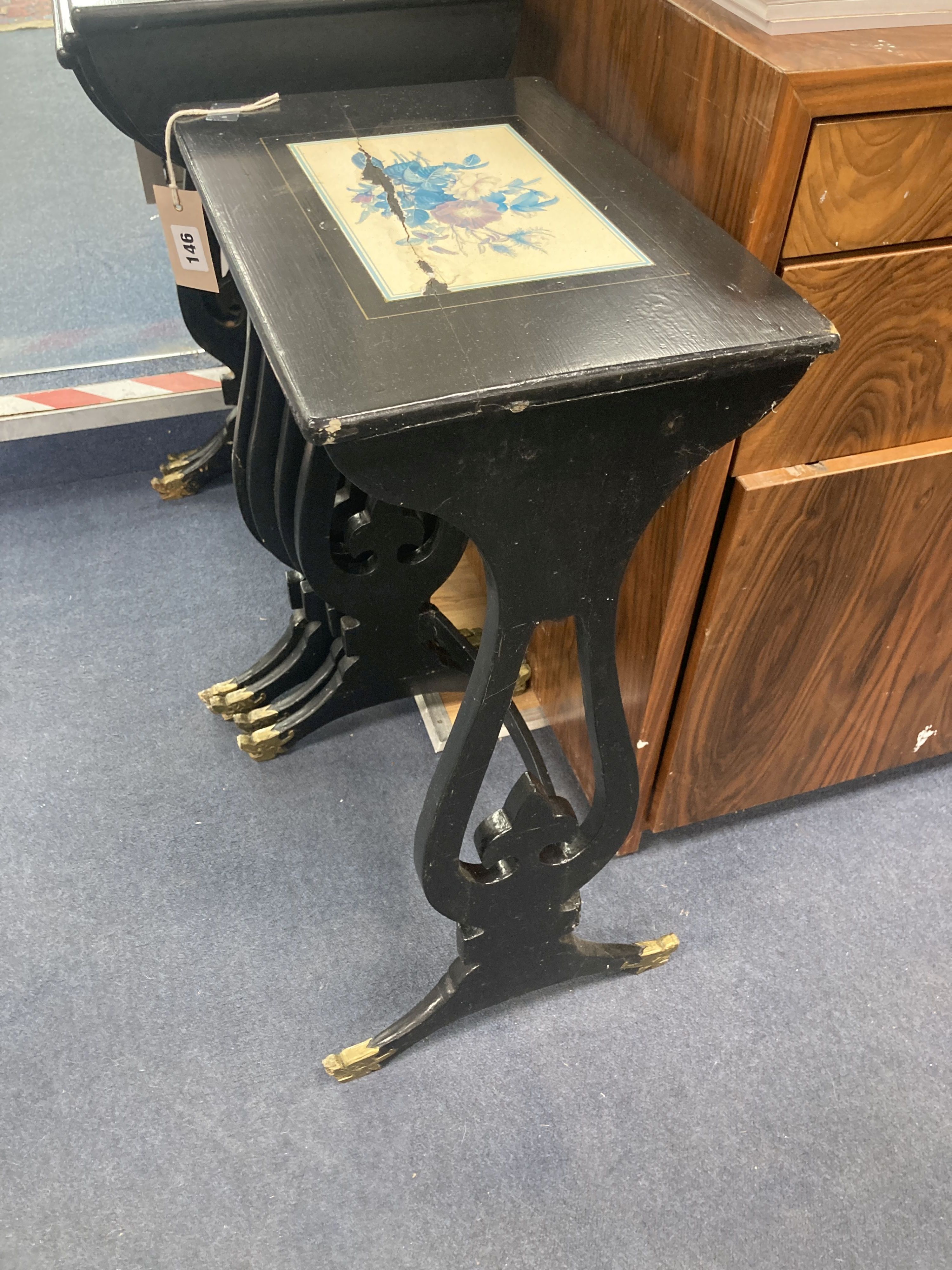 A graduating nest of four Regency style occasional tables with lyre shaped supports, black painted finish with gilt mask detail to supp